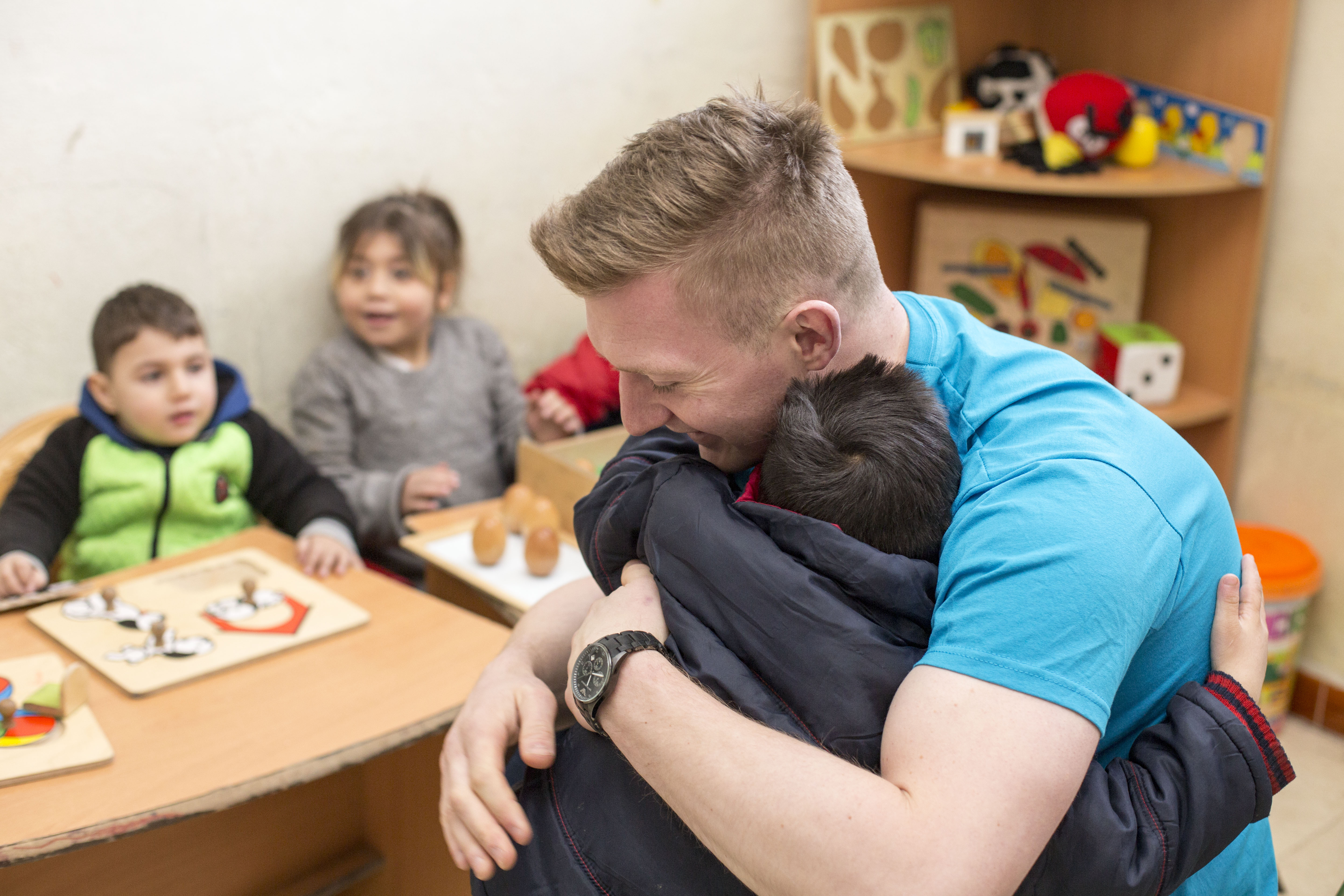 A man hugs a child in a playroom