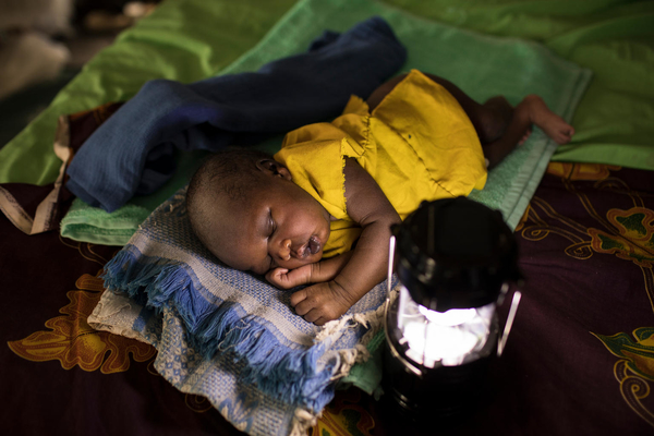a young baby is sleeping on a blanket near a light