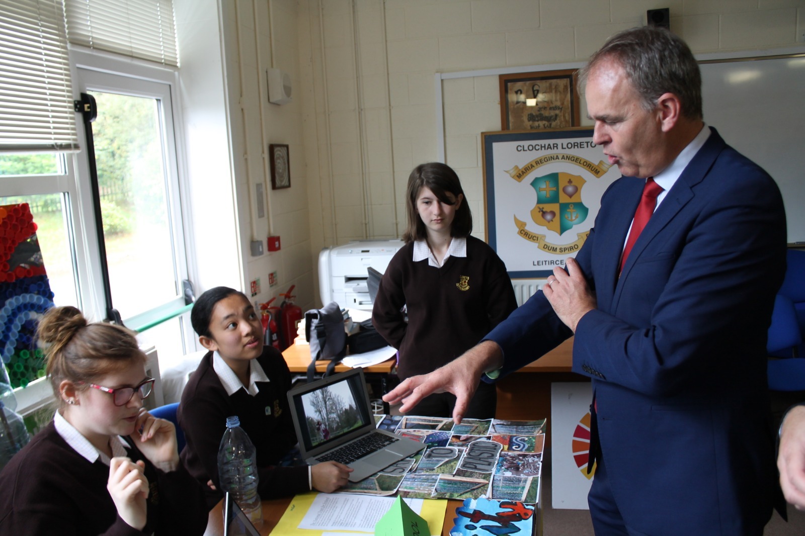 a man is talking to students sitting behind a table