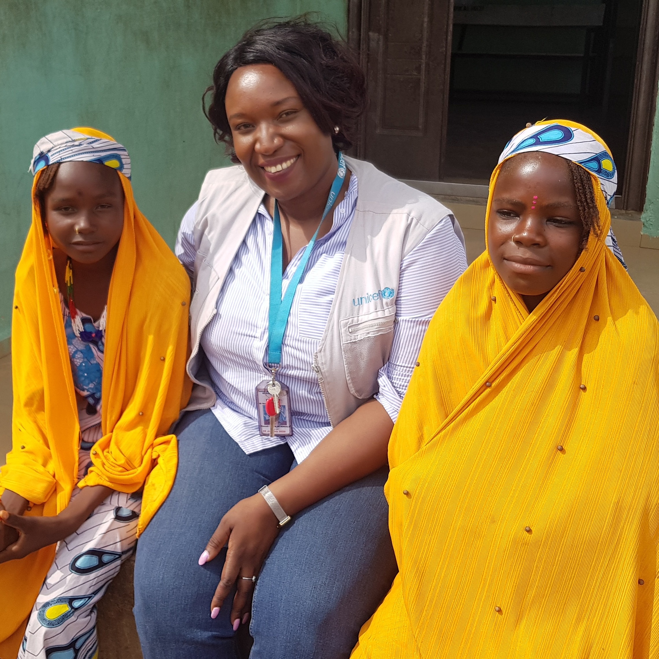 two girls are sitting with a UNICEF worker