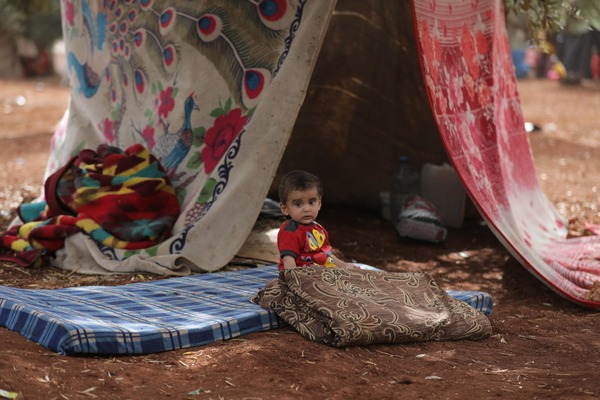 a  young boy is sitting on a mattress in front of a tent 