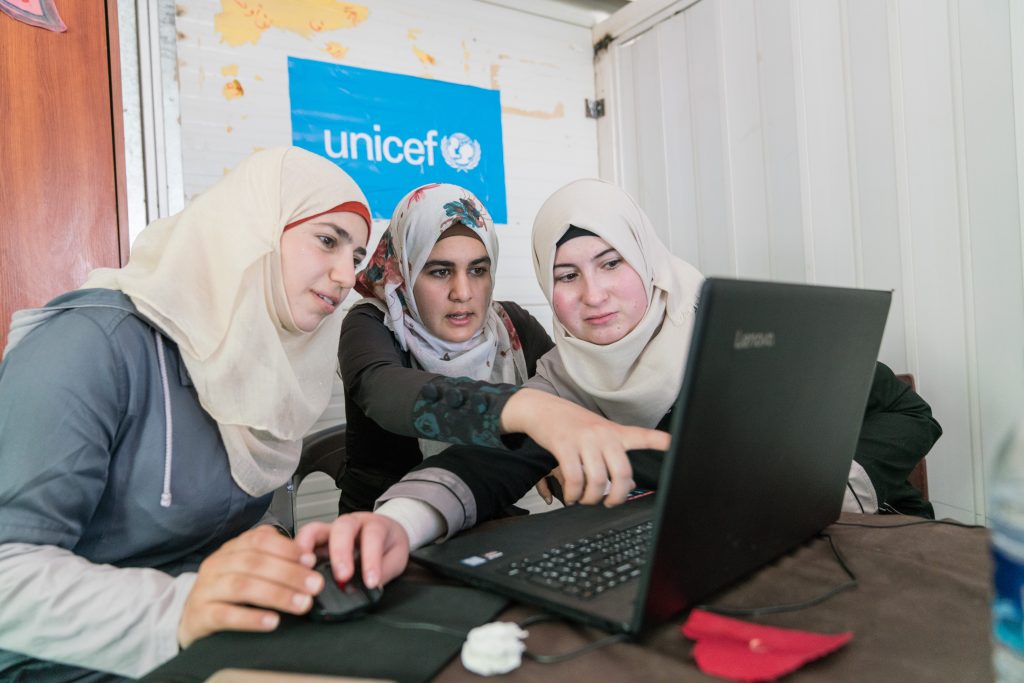 Three women are working on a laptop