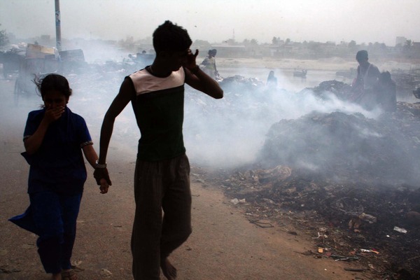 A boy is holding the hand of a little girl in front of a burning area