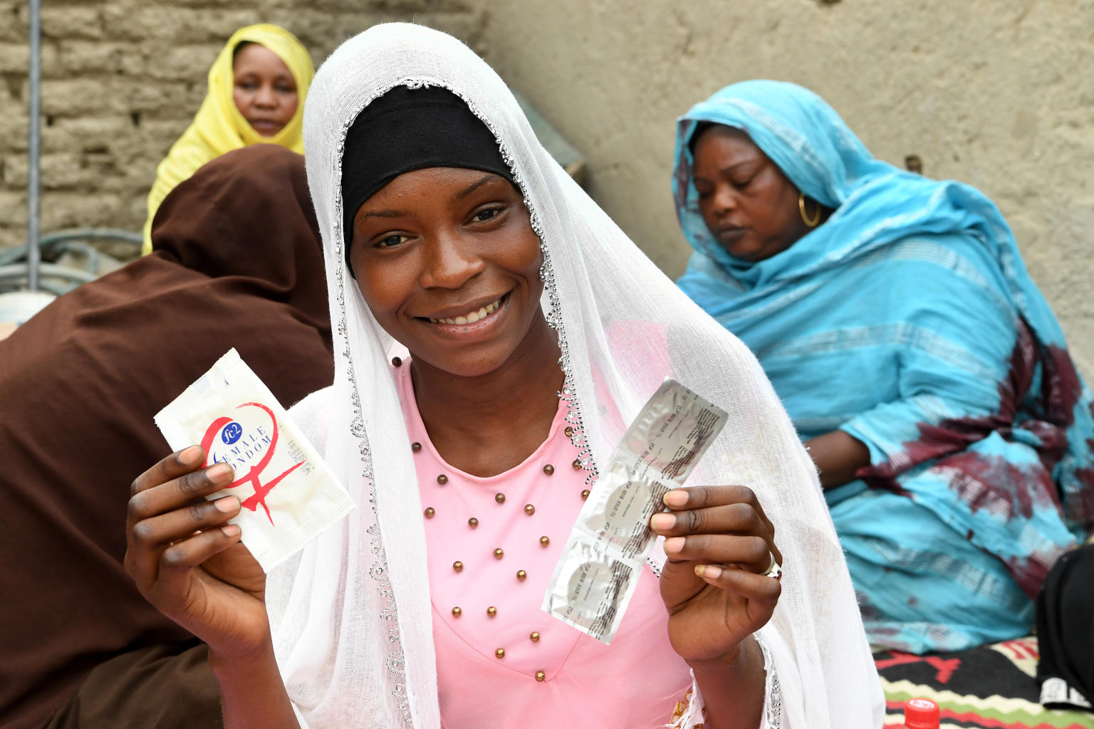 A teenage girl is showing condoms and smiling