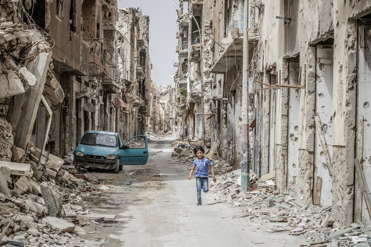 A child runs through the debris in a destroyed town