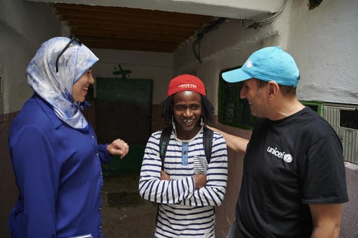 Three adults are standing smiling in an empty building