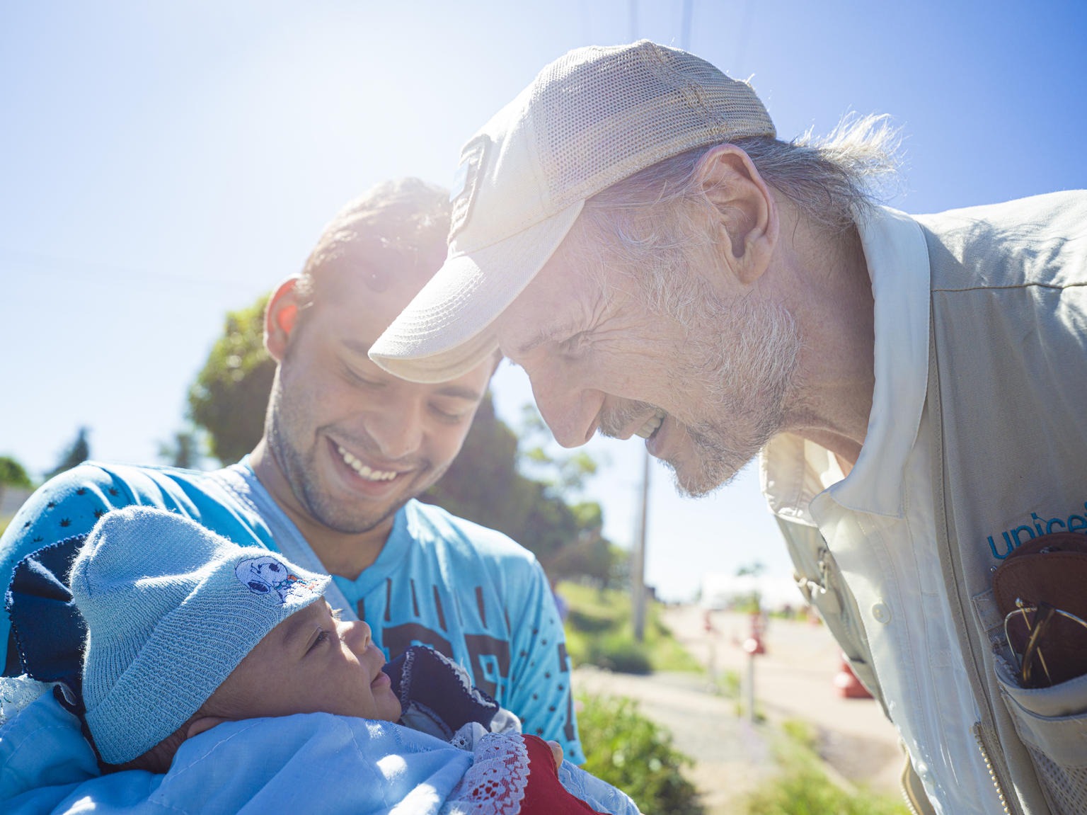 a man is bending smiling towards a newborn