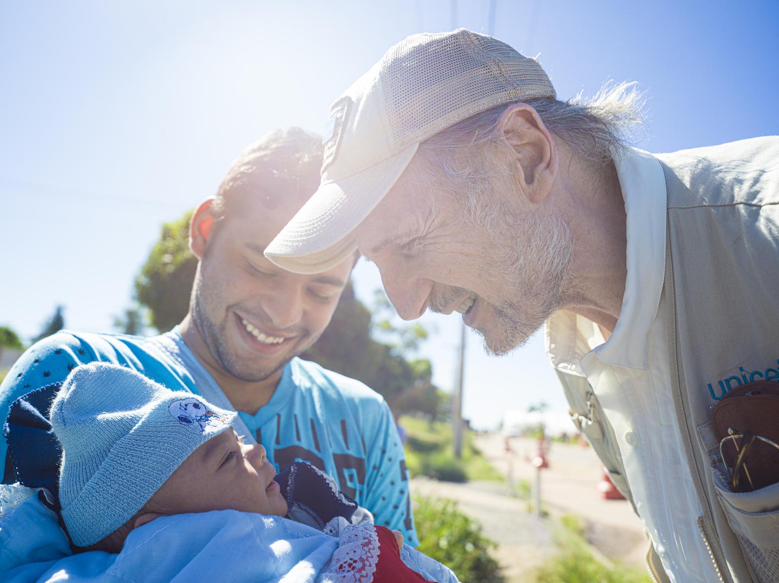 a man is bending smiling towards a newborn 