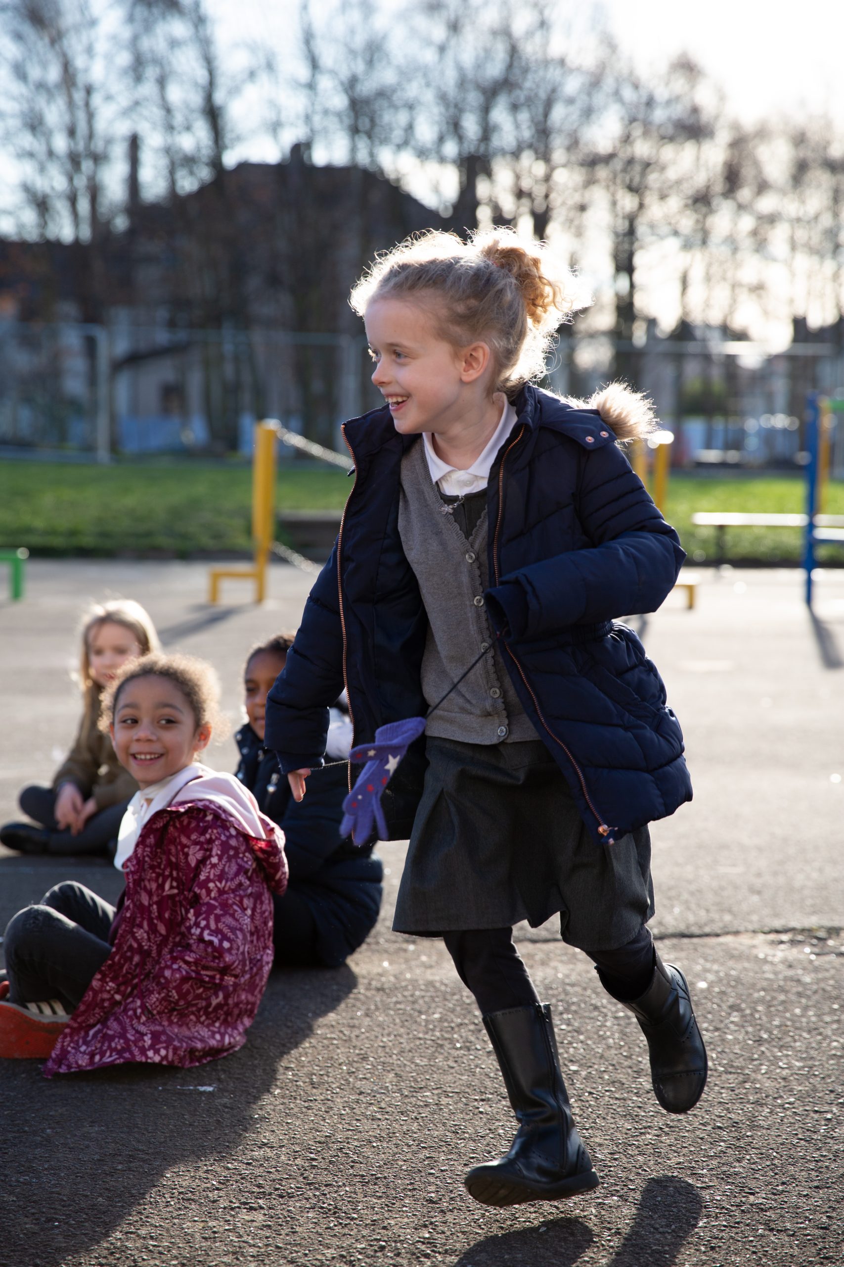 a young girl is running around her friends in a playground