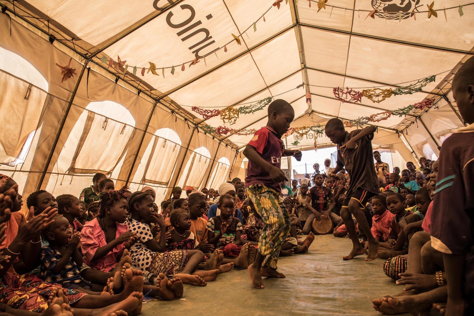 Children are dancing in an UNICEF tent