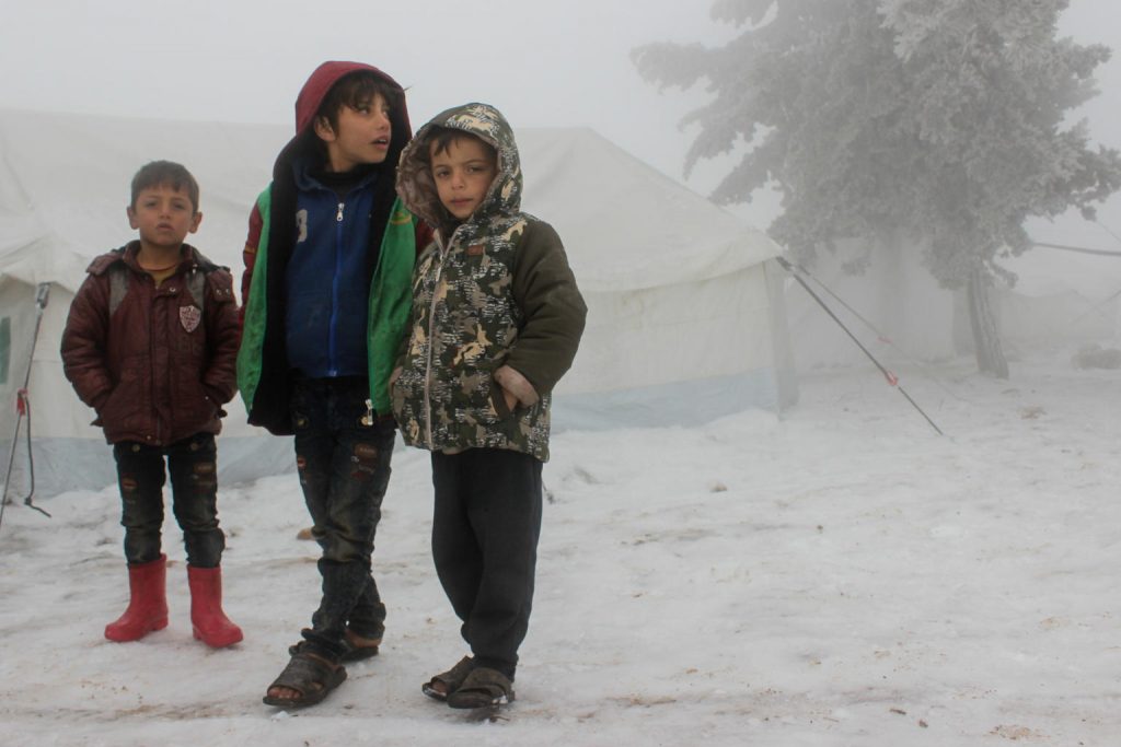 Three Boys are standing together under a snow blizzard