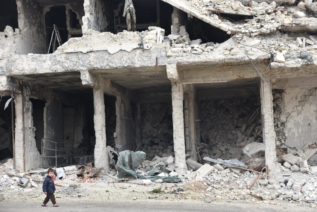 a child is walking through a destroyed building 