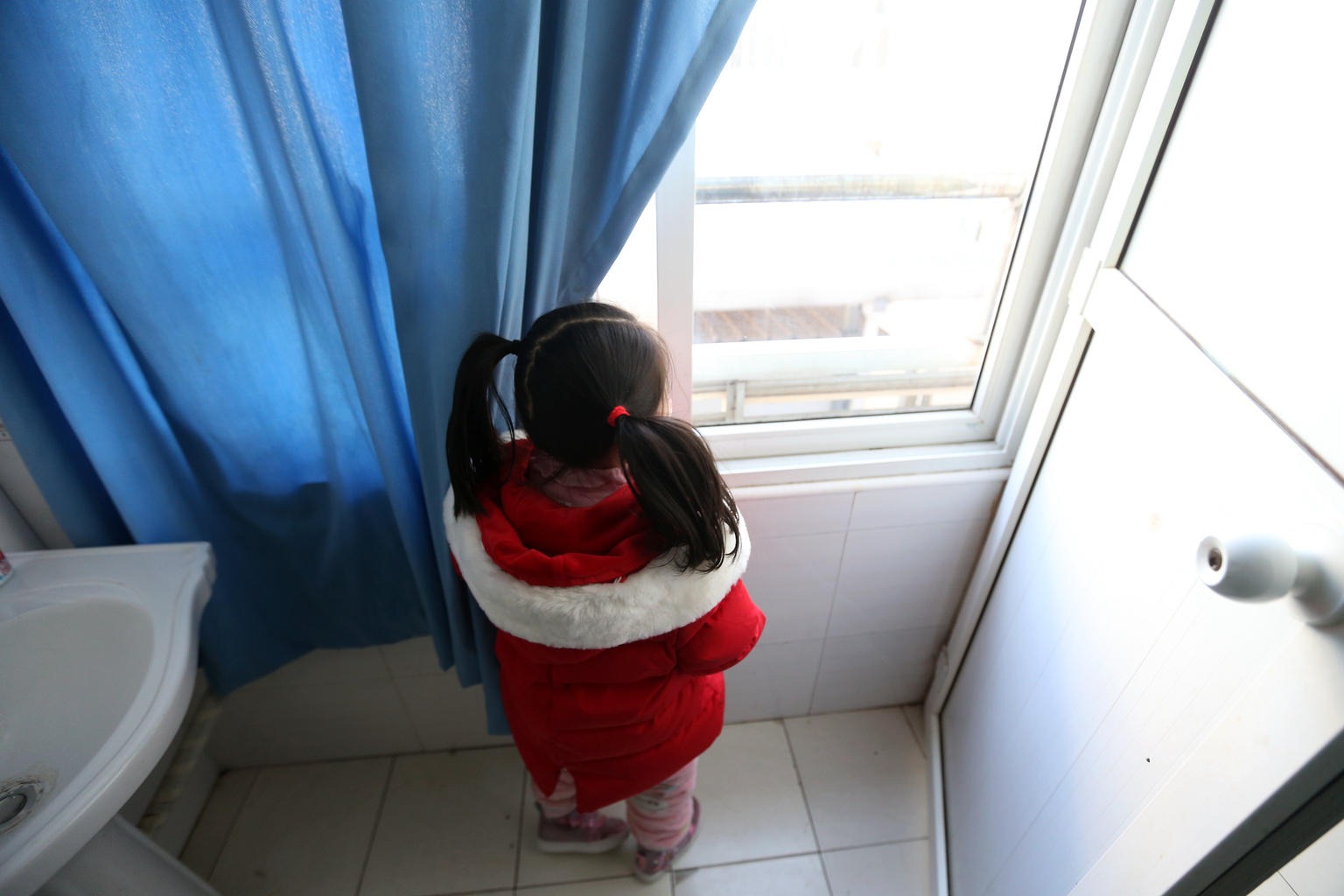 a young girl is looking by the window in a bathroom 