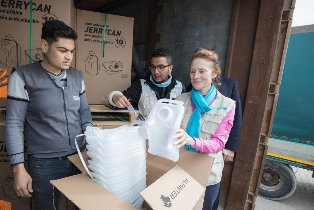 a man and a woman are opening a UNICEF box with UNICEF Wash products