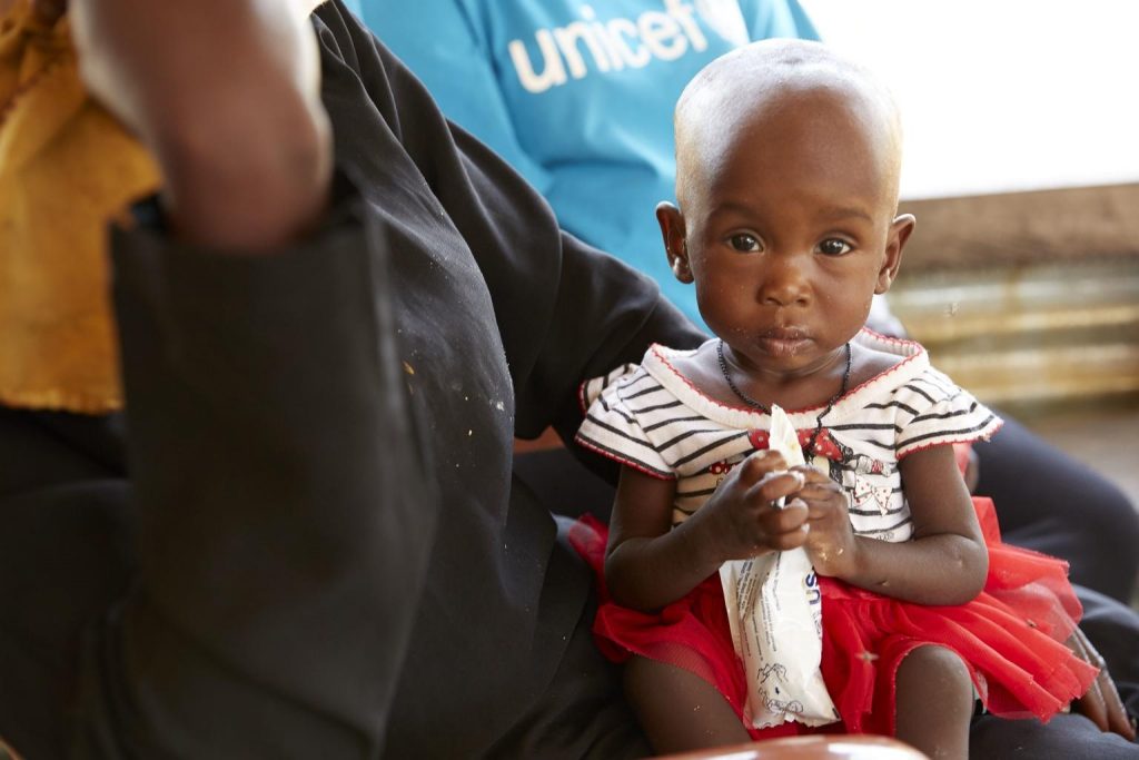 amira sits on her mothers lap at a unicef clinic