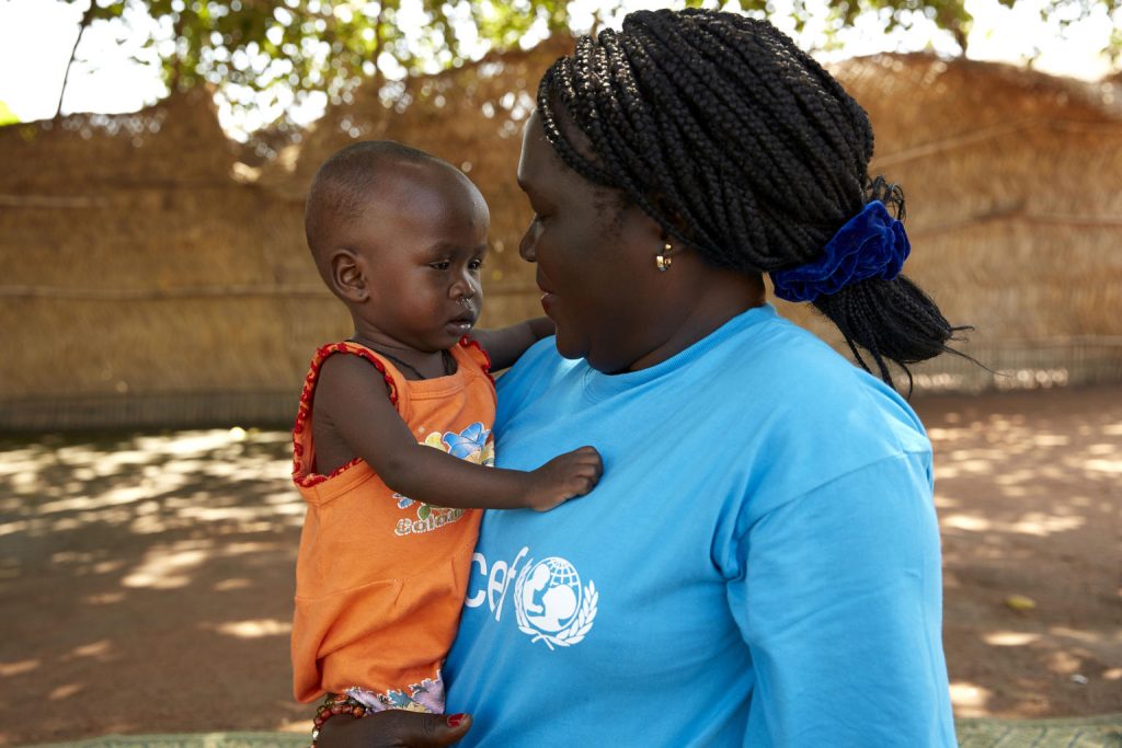 Amira is being held by UNICEF nutritionist Jesca 