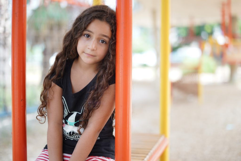 A little girl is looking at the camera sitting in a play zone