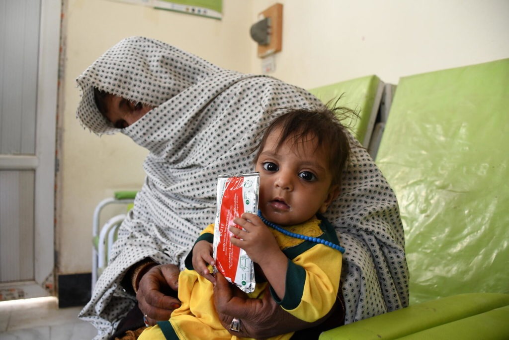 child holds a packet of peanut paste