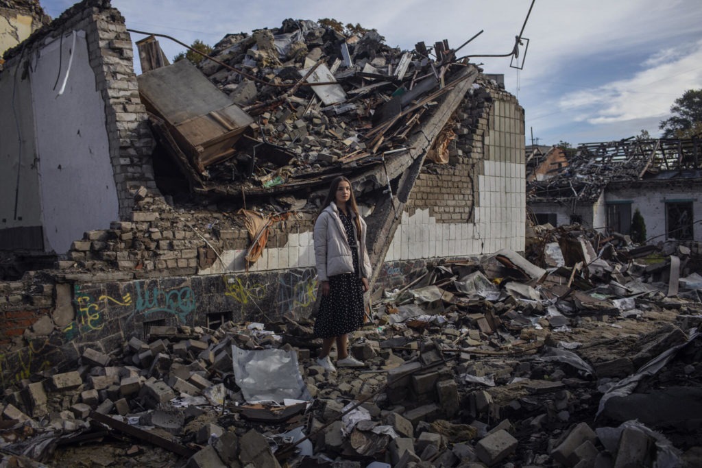 child stands amongst rubble in Ukraine