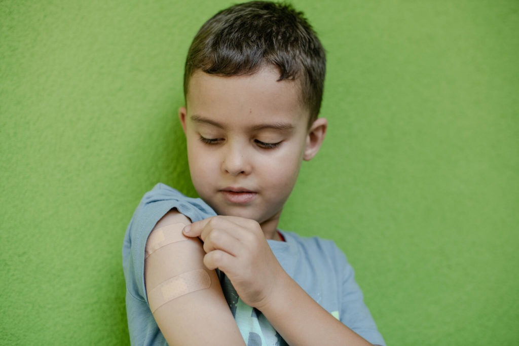 boy shows arm where he received injection