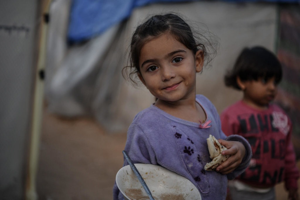 Israa, a 3-year-old, eats a piece of bread while standing in front of her family’s tent in Khan Younis city, south of the Gaza Strip. “The very loud sounds of bombing scare me. A big fire comes out. I'm afraid it will burn me,” Israa says. “I want my toys and my bed, not this tent” she added.