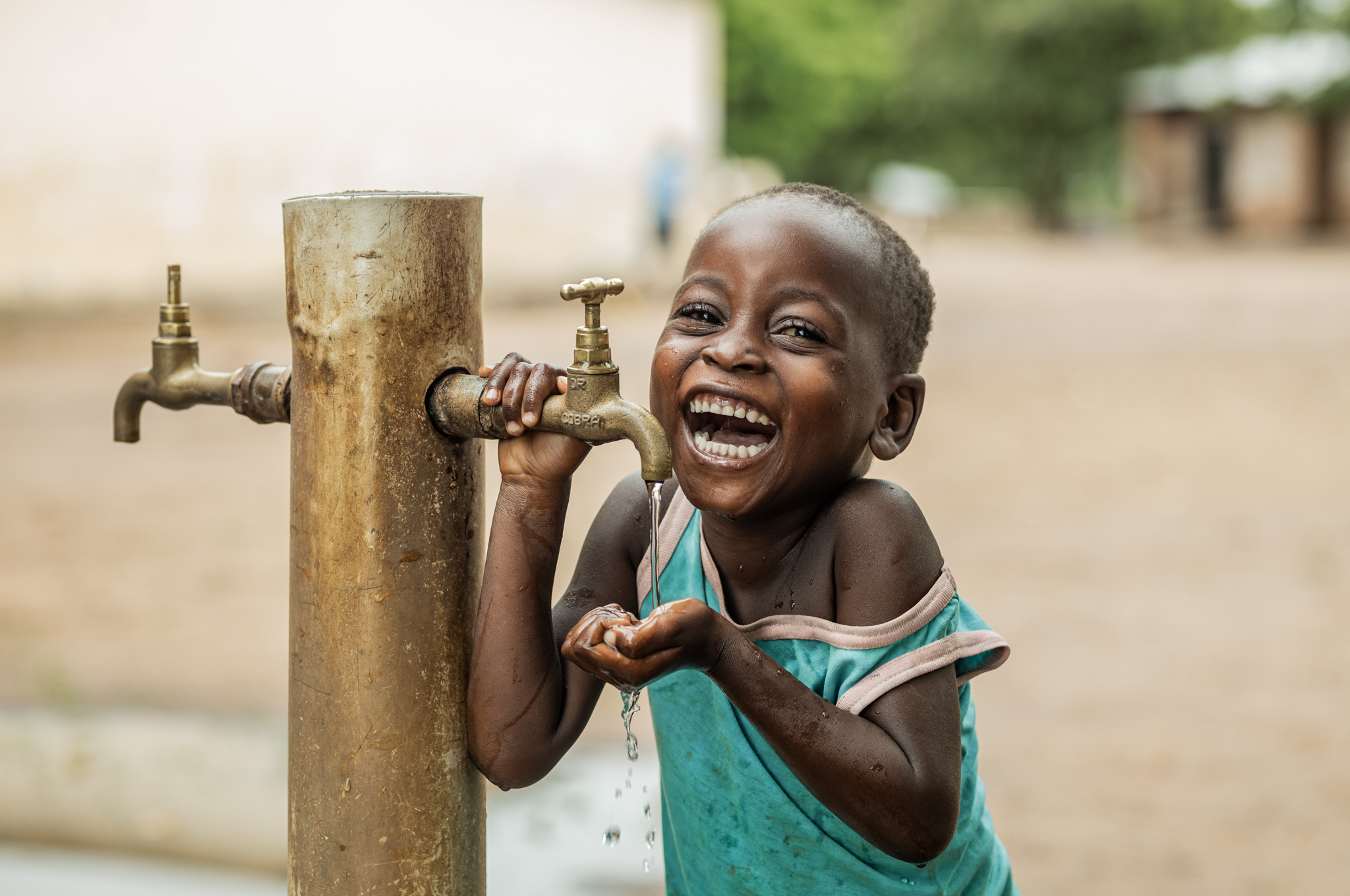 child smiling while drinking water from tap