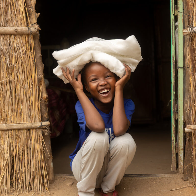 A child smiles after receiving a new bed net at her home in Arabee neighbourhood in Sudan.
