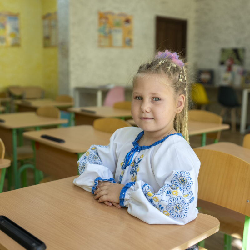 Alessa, age seven, sits at a desk in her classroom at Zlatopil Lyceum No. 6 in the Kharkiv region of Ukraine.