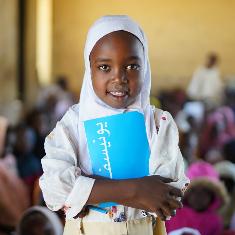 Seven-year-old Aya stands in a classroom in Sudan where children who fled the war in Al Fasher received scholastic materials like books, pens, colours and pencils.
