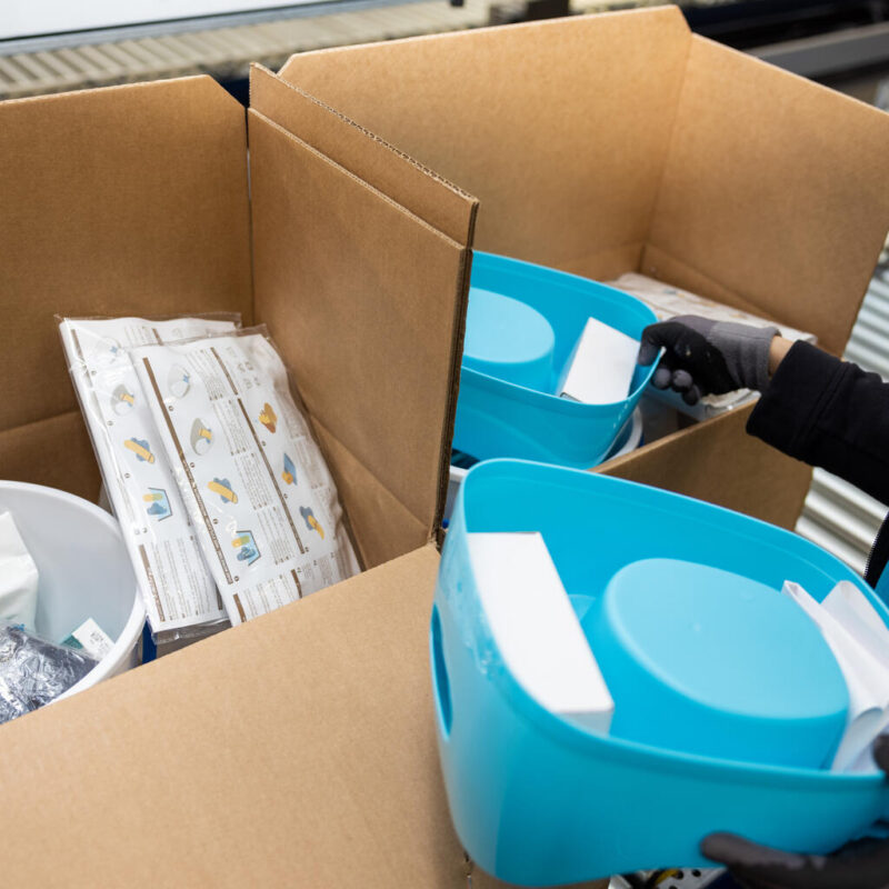 Boxies are filled up with hygiene kits for families. Items in the kit include water containers, a bucket, a child’s potty, soap, water purification tablets, a torch, sanitary pads, underwear and laundry detergent.